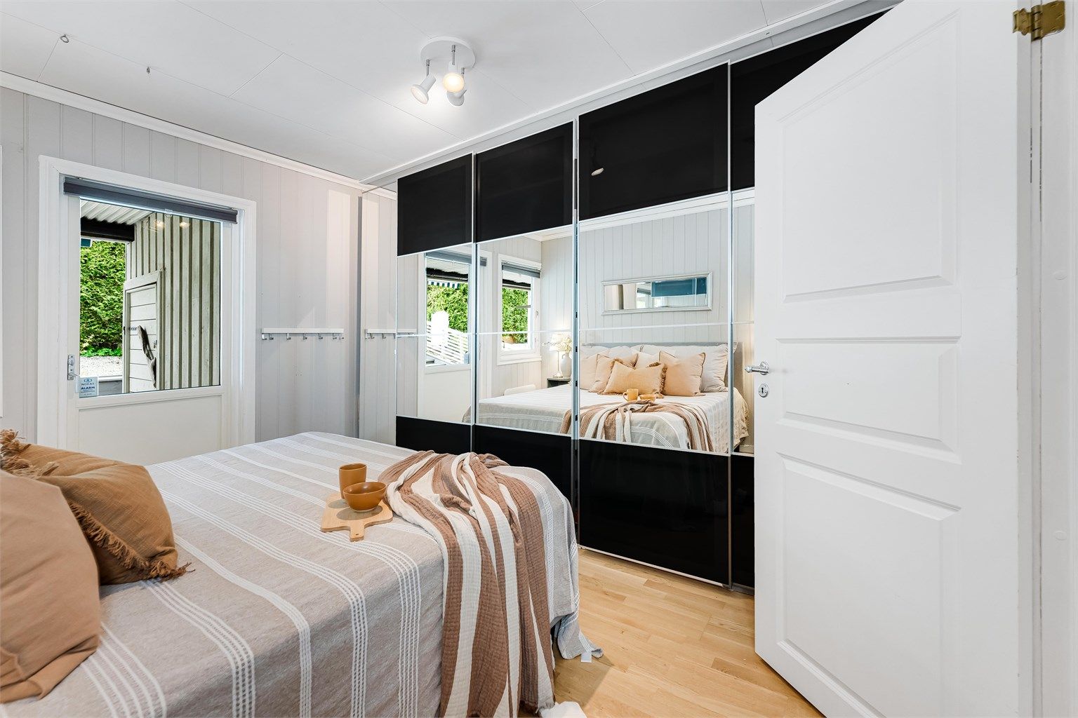 Stor skyvedørsgarderobe med speilfronter og tilkomst til uteplass/terrasse fra altandør.
