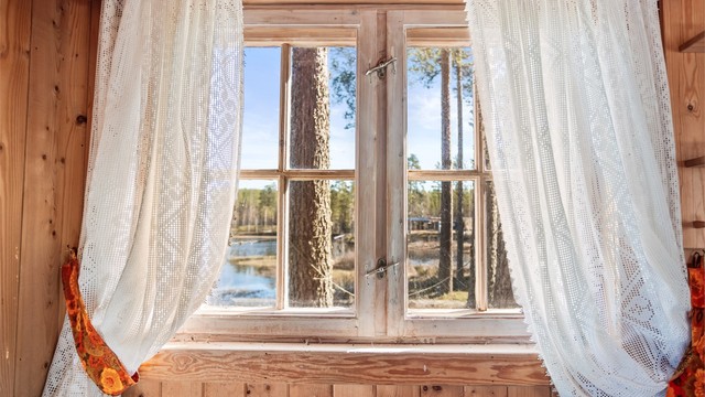 Koblede vinduer med trerammer slipper inn dagslys og gir utsikt mot skogen.