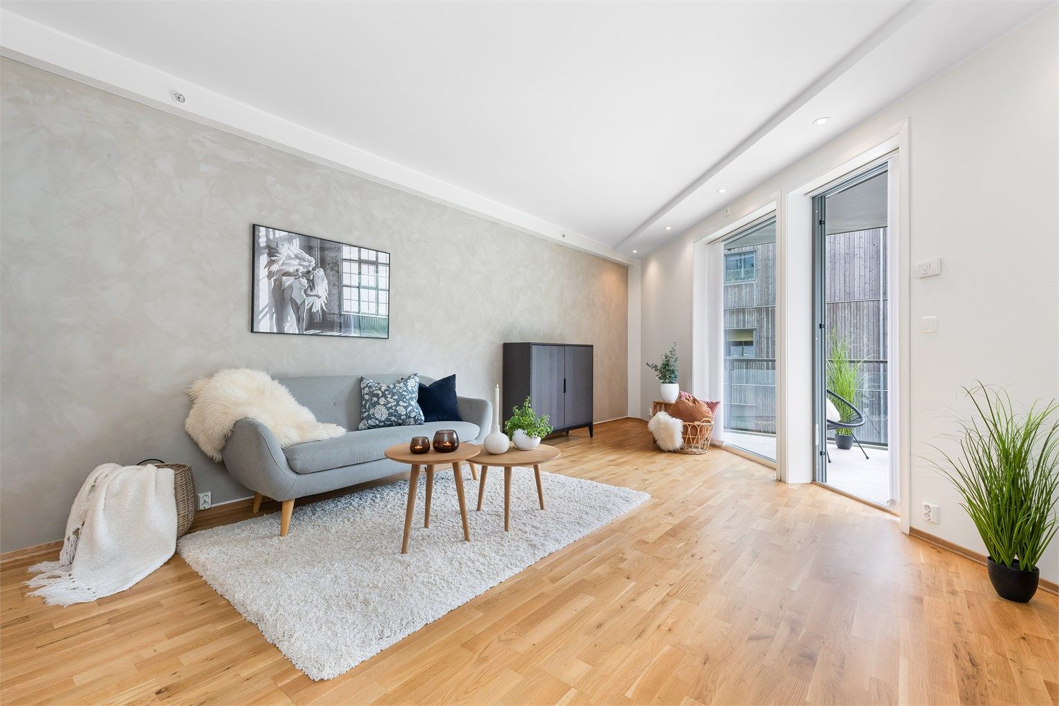 Stuen har spotter i tak og store vindusflater som gir godt med lysinslipp. Kalkmalingen på veggen skaper en behagelig atmosfære.