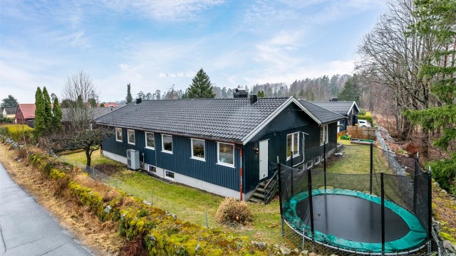 Boligen ble i 1974 oppført på en stor hjørnetomt helt innerst på feltet. Den er innholdsrik og har de fleste oppholdsrom på én flate i første etasje, i tillegg til stor kjeller med ytterligere rom. Fotograf; Børge Oppegård.