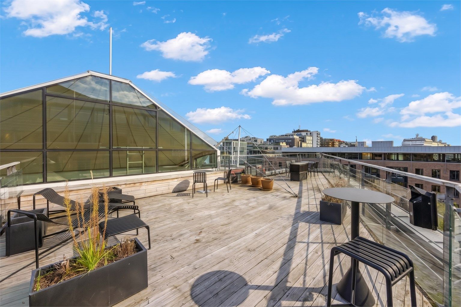 Felles takterrasse opparbeidet med terrassebord og solstoler.