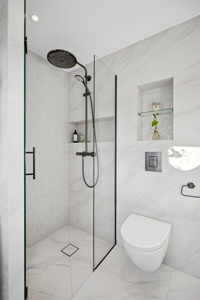  Dusjnisje med glassdør og ettgreps dusjarmatur, samt vegghengt toalett med innebygget sisterne. 