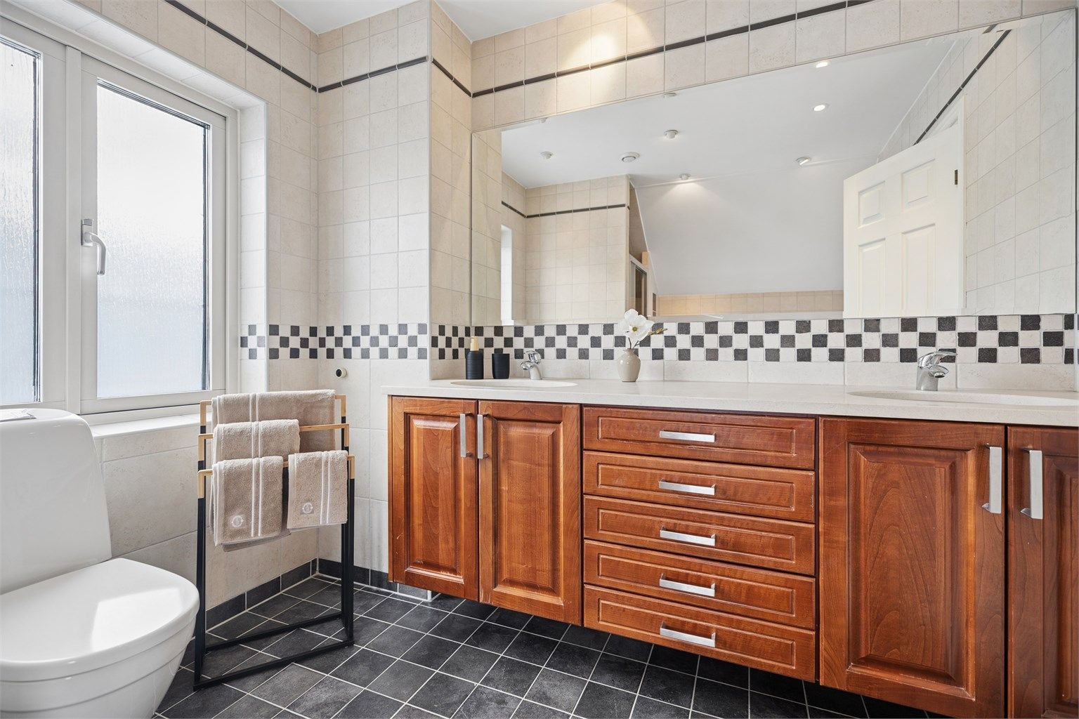 Badet i 2. etg  med delikat baderomsinnredning med dobbel servant, hel benkeplate i steinmateriale og rikelig med skap- og skuffeplass. Flislagte overflater, gulvvarme og downlights bidrar til et eksklusivt og komfortabelt uttrykk