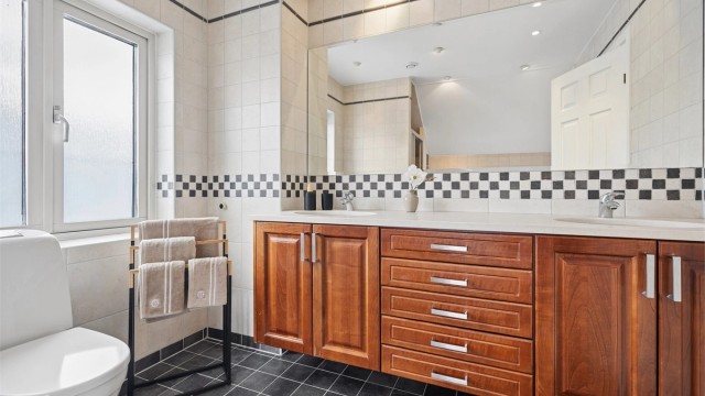 Badet i 2. etg med delikat baderomsinnredning med dobbel servant, hel benkeplate i steinmateriale og rikelig med skap- og skuffeplass. Flislagte overflater, gulvvarme og downlights bidrar til et eksklusivt og komfortabelt uttrykk