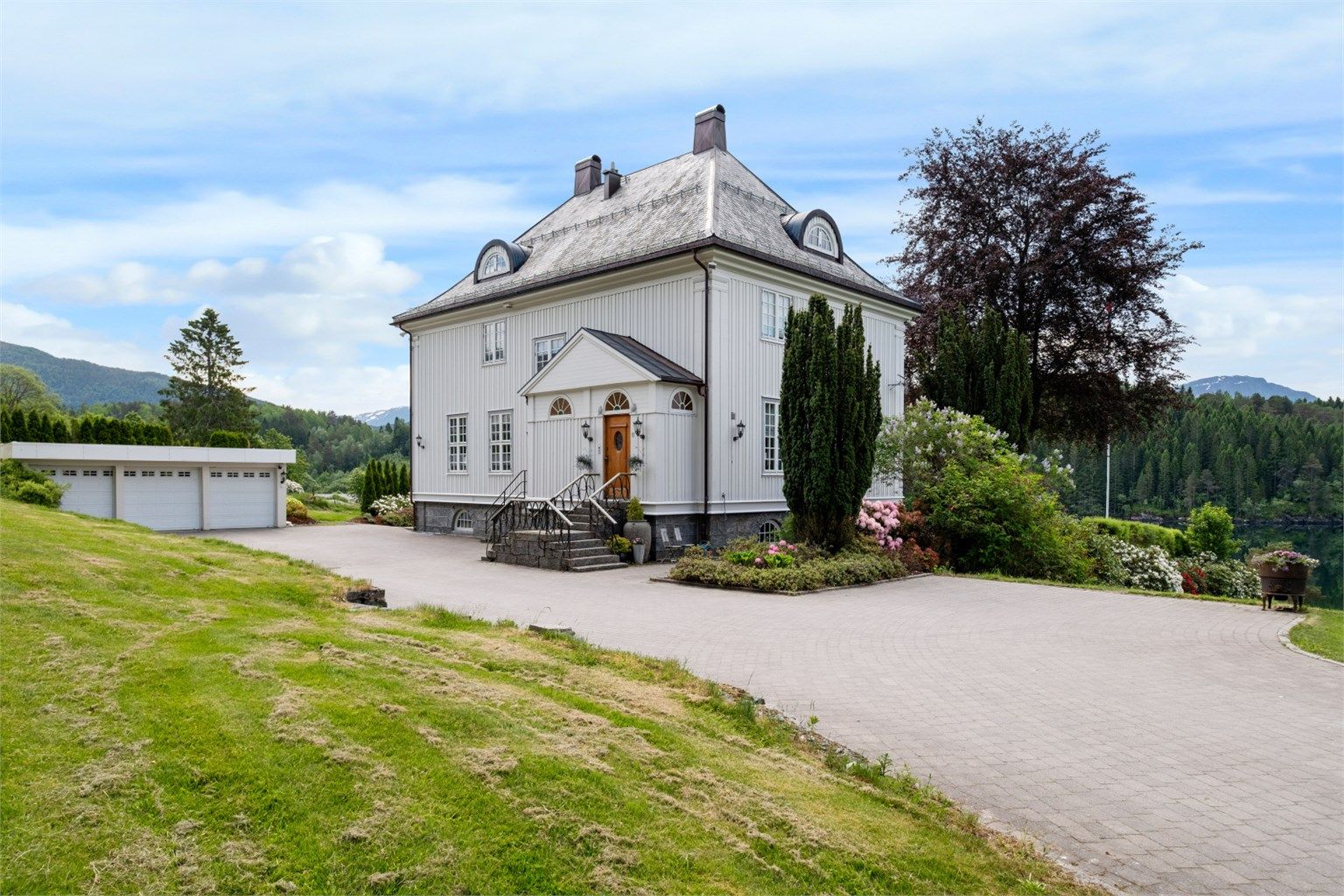 Ankomsten via en gårdsplass med belegningsstein fra 2014 leder til hovedinngangen og en stor garasje