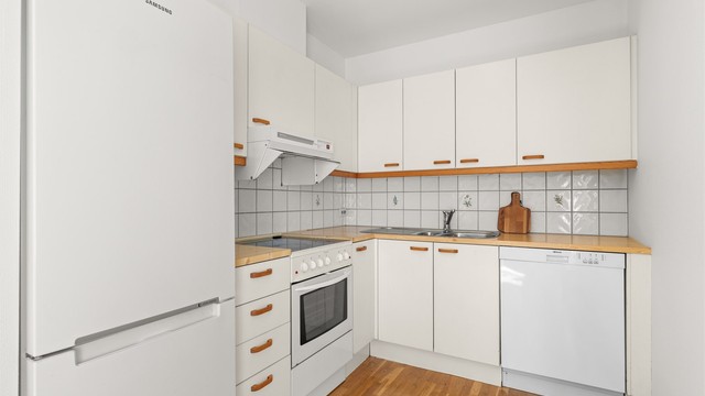 Kjøkkenet har åpen løsning mot spisestuen og fremstår funksjonelt med innredning med glatte fronter og laminert benkeplate.