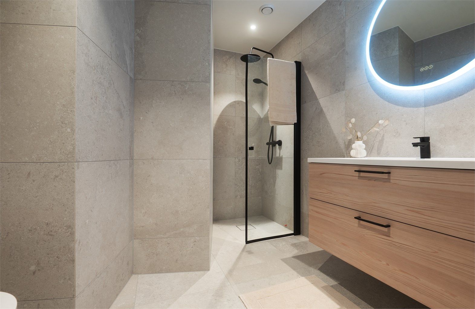 Dusjsonen i til mastersoverommet har mosaikkfliser på gulvet og dusjvegger i klart glass.