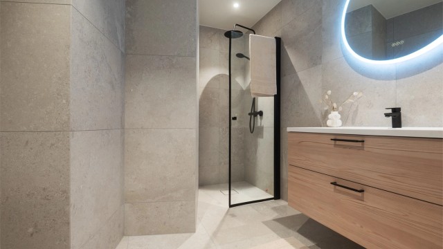 Dusjsonen i til mastersoverommet har mosaikkfliser på gulvet og dusjvegger i klart glass.