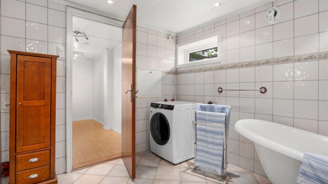 Romslig bad med badekar og opplegg for vaskemaskin.