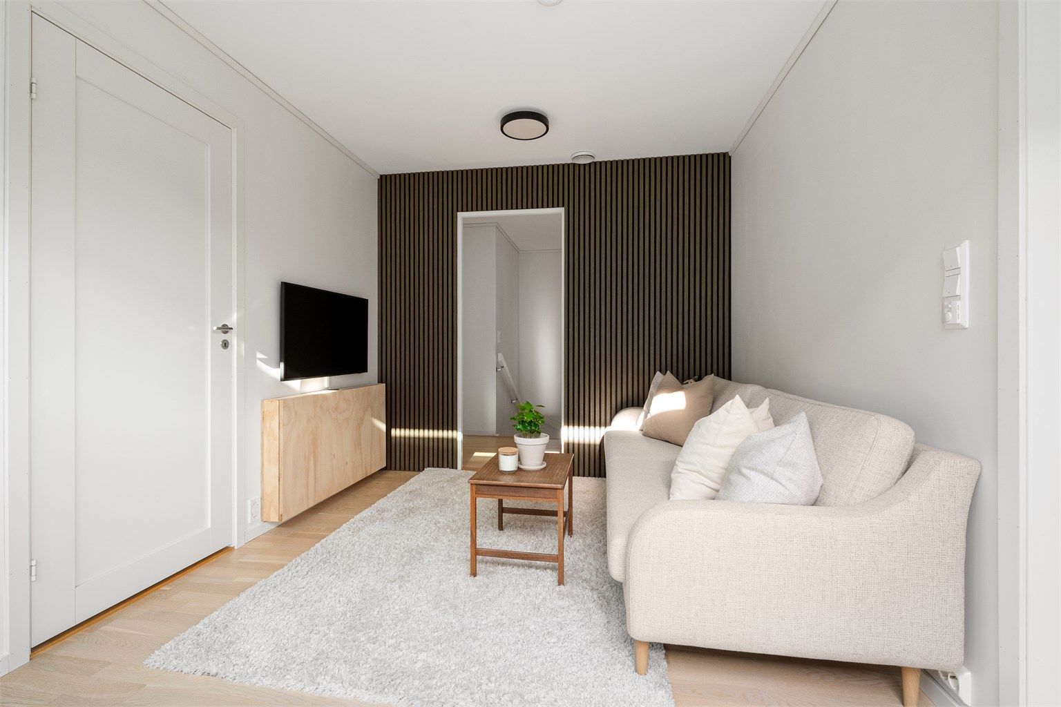 Loftstuen har parkett på gulv, dekorativ spilevegg og plass til sofagruppe.