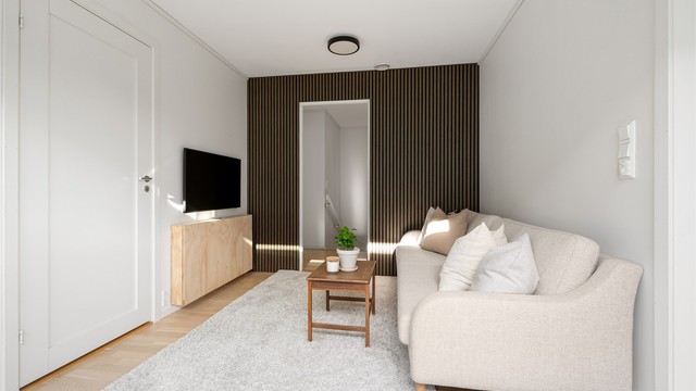 Loftstuen har parkett på gulv, dekorativ spilevegg og plass til sofagruppe.