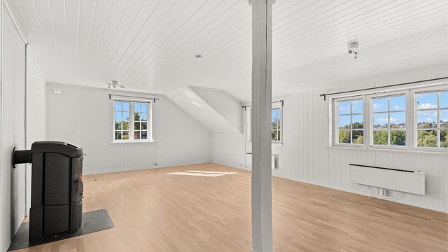 Stuen har sjarmerende detaljer med synlig trestolpe og panelte himlinger.