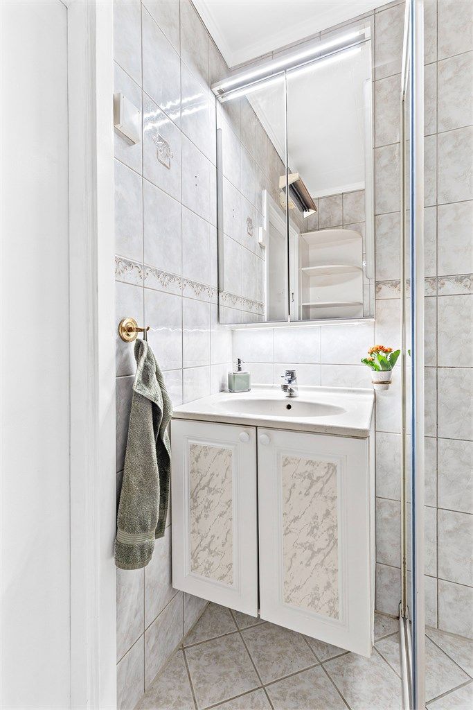 Badet er innredet med vegghengt servantskap med ettgreps armatur og speilskap med belysning.