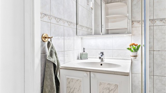 Badet er innredet med vegghengt servantskap med ettgreps armatur og speilskap med belysning.
