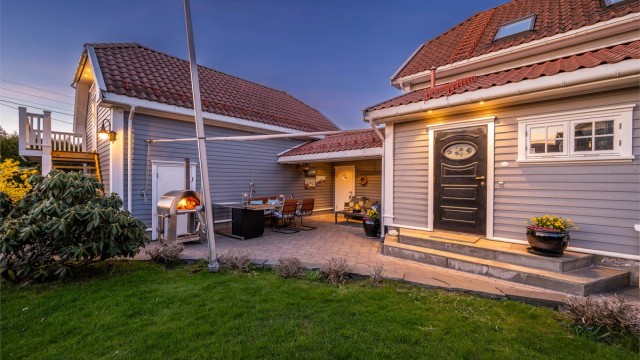 Mellom boligen og garasjen er det etablert en lun og overbygd uteplass med belegningsstein.