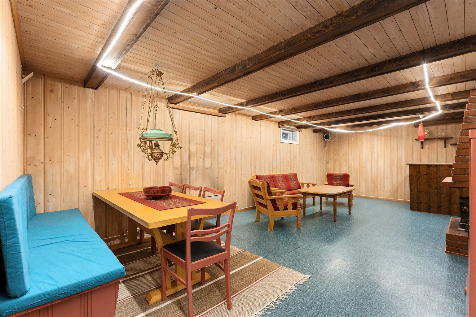 Romslig kjellerstue med plass til både sittegruppe og spisebord.