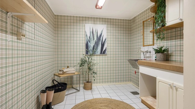 Romslig vaskerom med flislagt gulv med gulvvarme og opplegg for vaskemaskin.