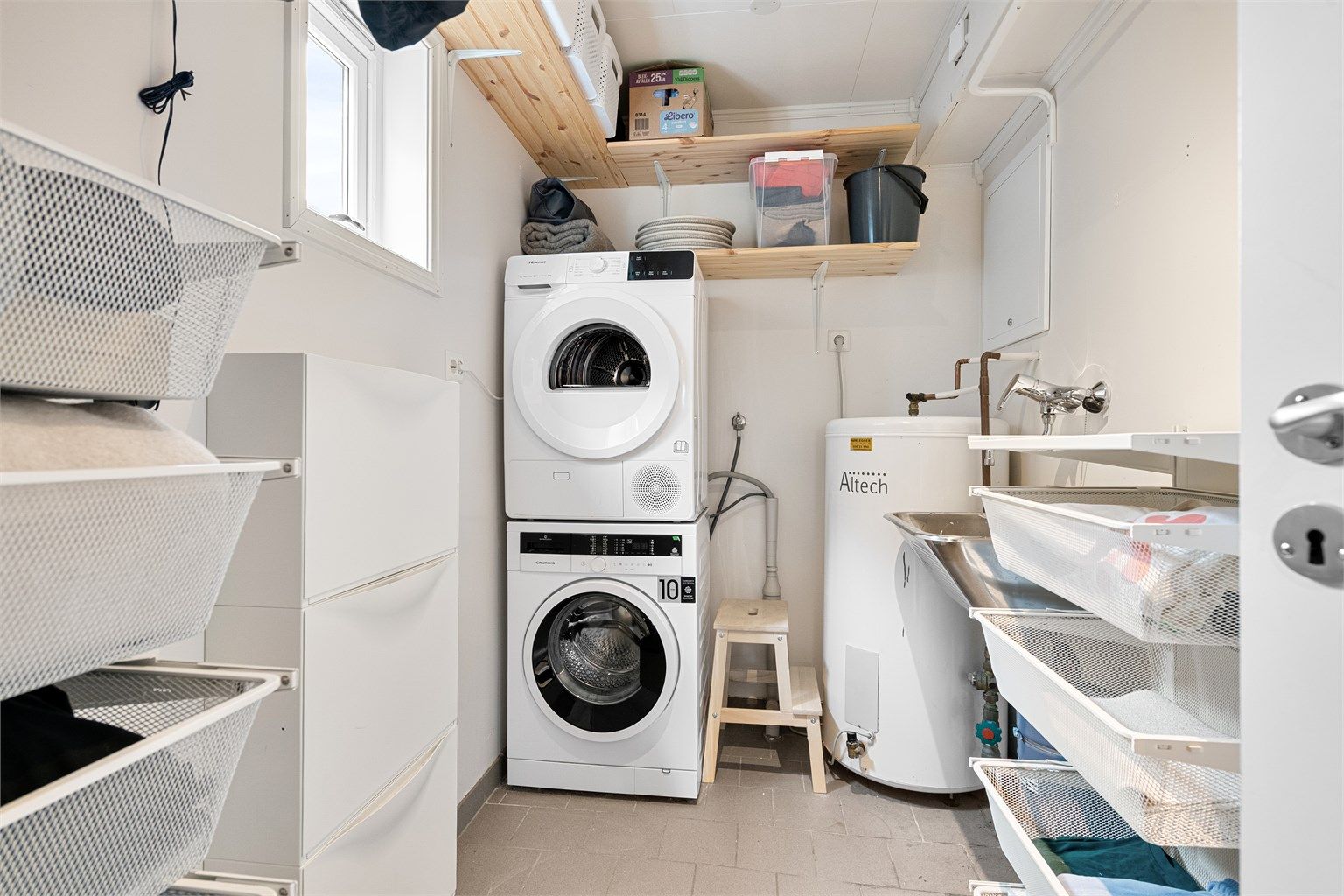 Praktisk vaskerom med opplegg for vaskemaskin og plass til oppbevaring.