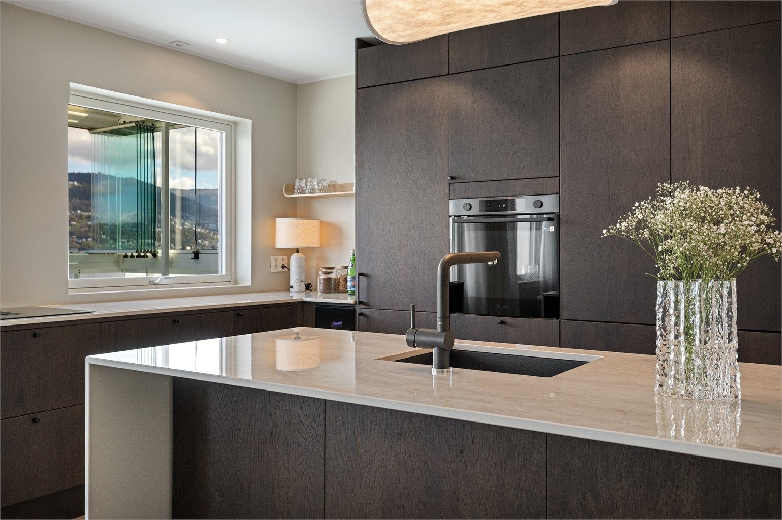 Den åpne kjøkkenøyen med nedfelt vask gir både ekstra arbeidsflate og en sosial sone mot resten av rommet. 