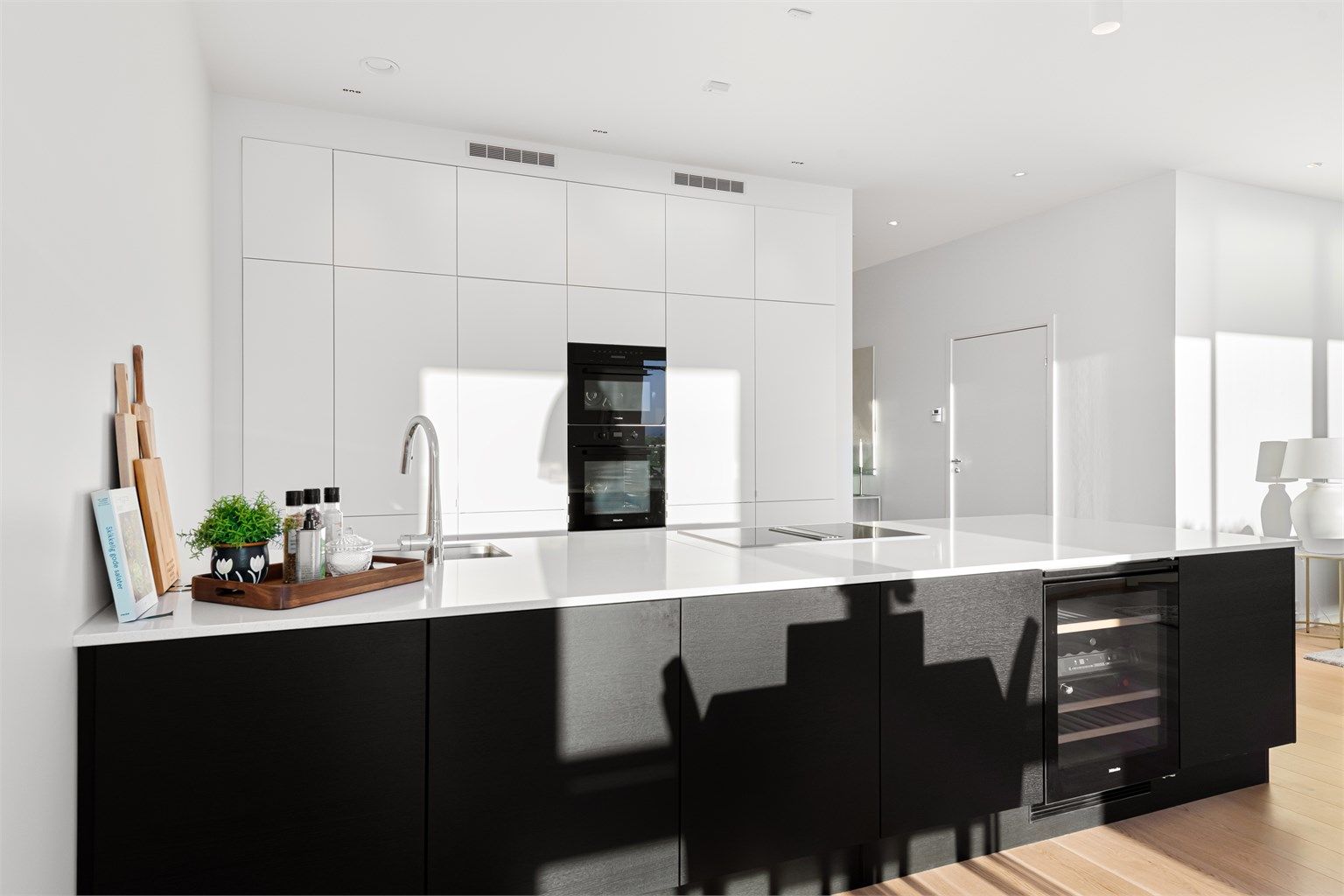 Kjøkkenet har integrerte hvitevarer fra Miele: 2 stk. kjøl/fryseskap (et av skapene har isbitfunksjon), oppvaskmaskin, induksjonstopp, vinskap, micro og stekeovn. Kjøkkenventilator med kullfilter men med avtrekk fra balansert anlegg fra kokesonen. 