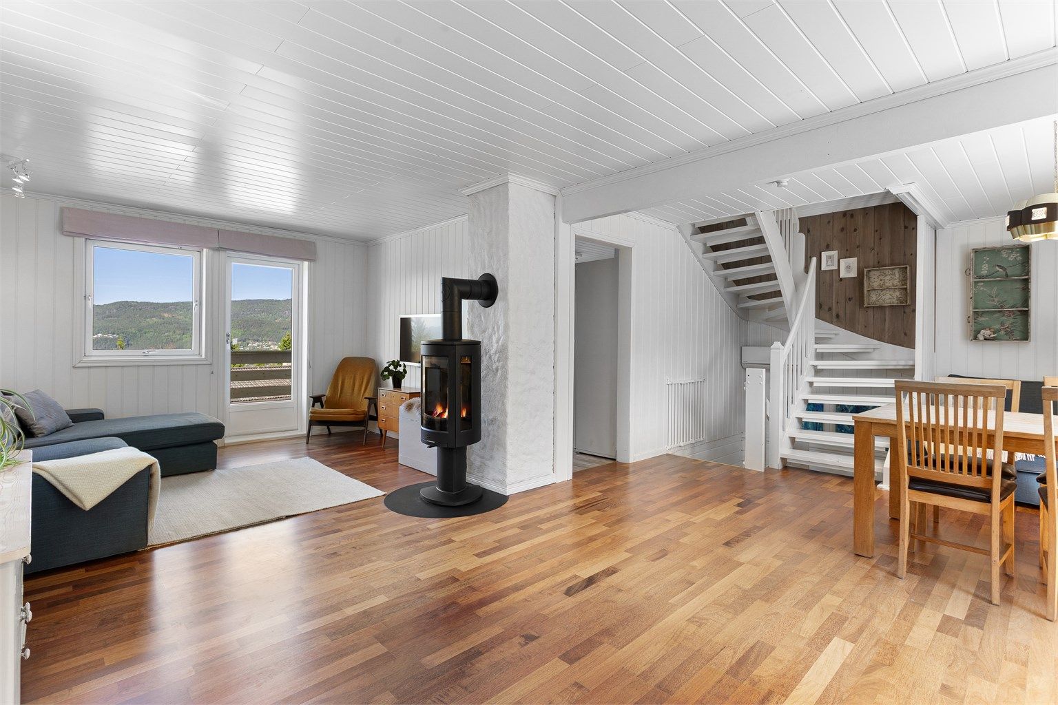 Lys stue med mye naturlig lys fra flere vinduer. Plass til sofagruppe og spisebord.