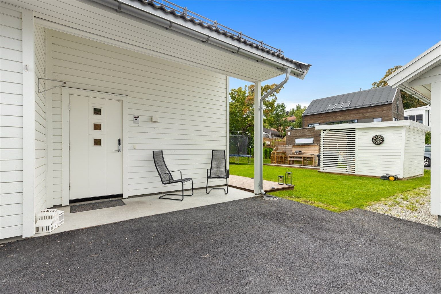 Overbygd inngangsparti og asfaltert gårdsplass.