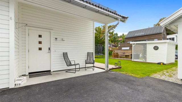 Overbygd inngangsparti og asfaltert gårdsplass.