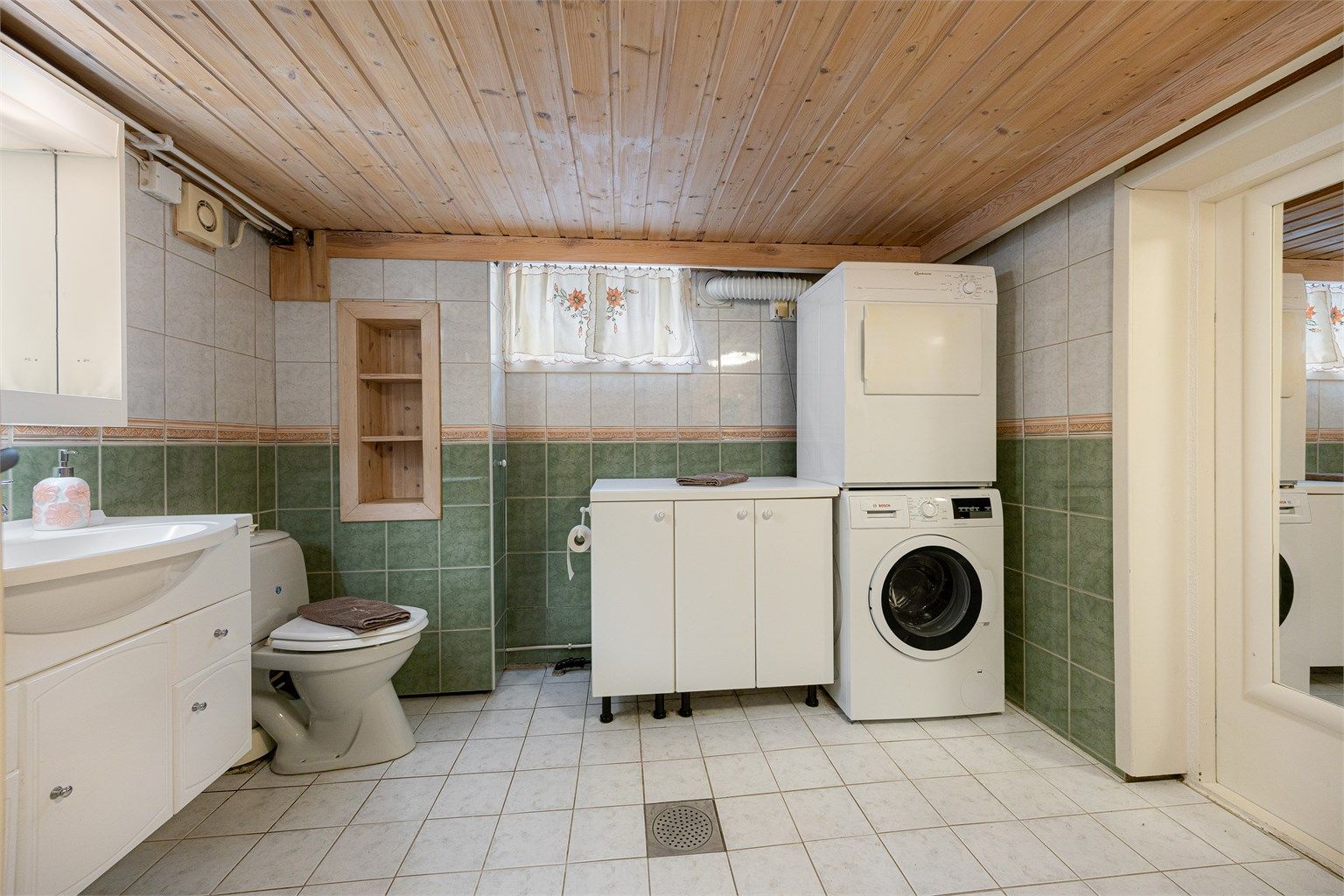 Badet i kjelleren har flislagt gulv og praktisk opplegg for vaskemaskin.