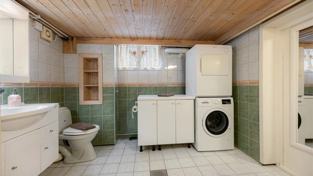 Badet i kjelleren har flislagt gulv og praktisk opplegg for vaskemaskin.