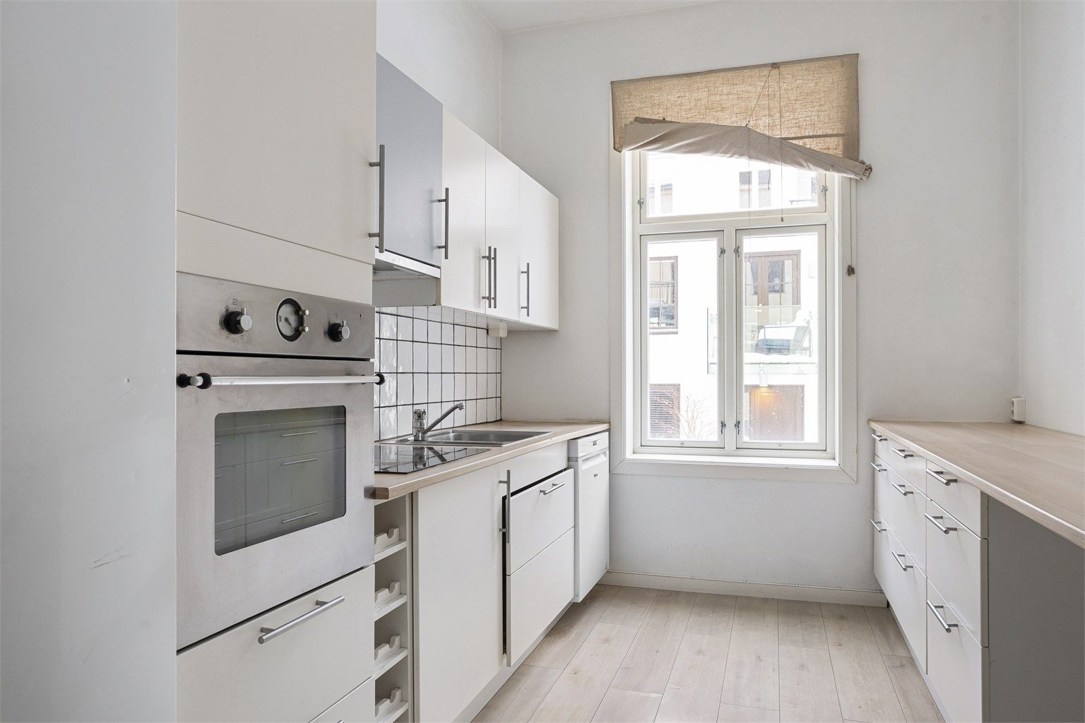 Praktisk kjøkken med hvite fronter og barløsning for spiseplass.