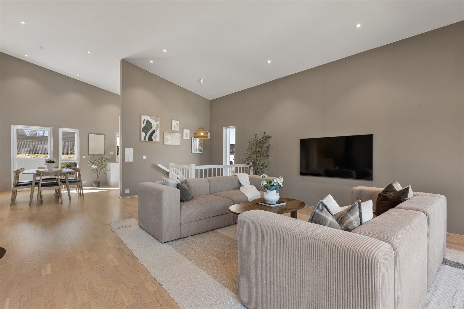 Den åpne løsningen mellom stue og kjøkken skaper en naturlig flyt og et sosialt allrom i boligens hovedetasje.