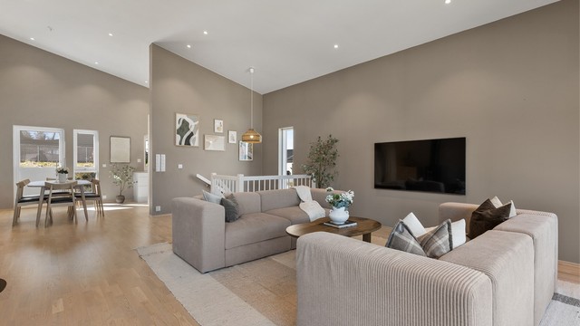 Den åpne løsningen mellom stue og kjøkken skaper en naturlig flyt og et sosialt allrom i boligens hovedetasje.