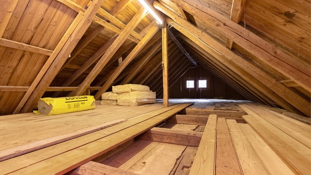 Uinnredet kaldt loft med synlige taksperrer, tredekke og rikelig med lagringsplass.