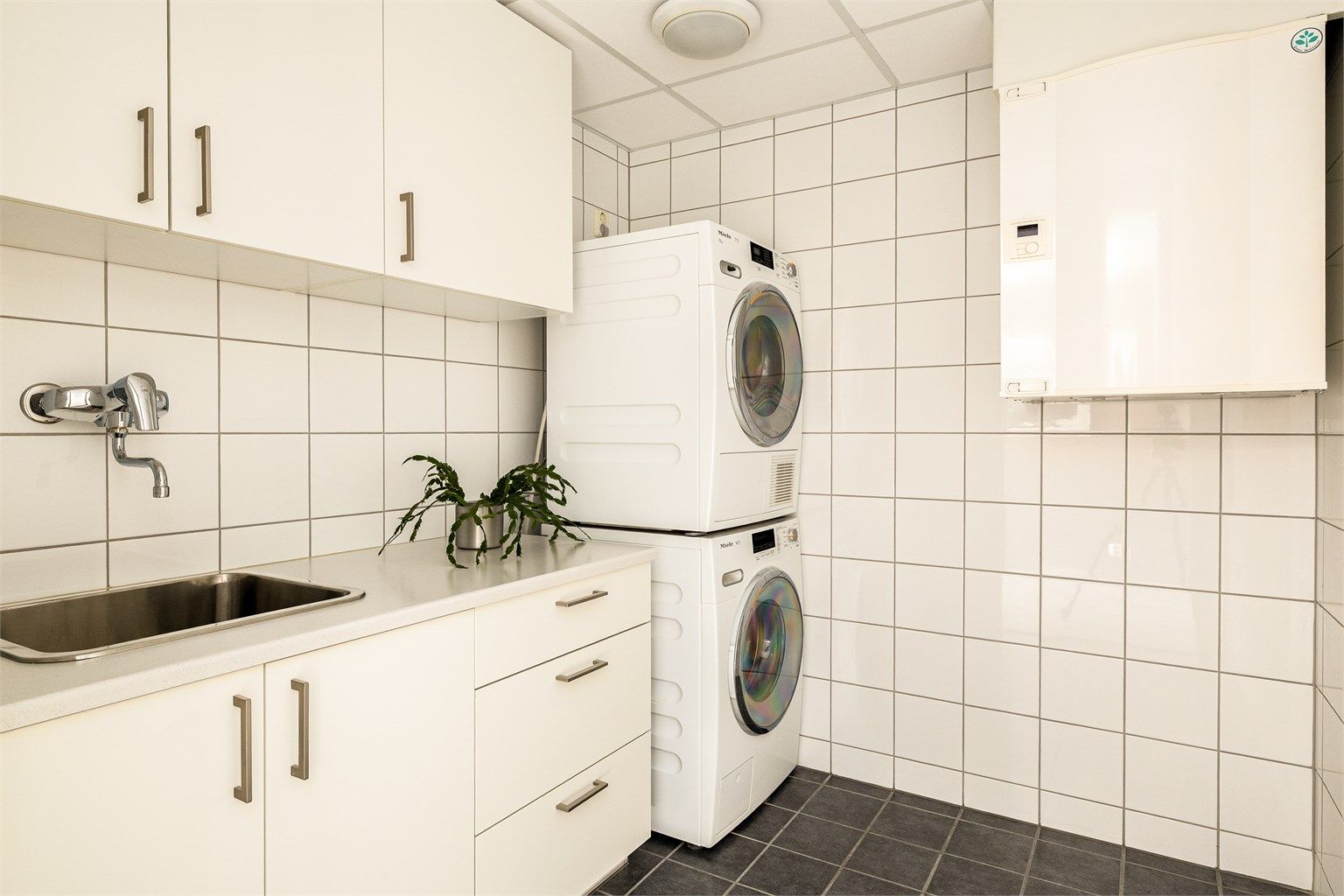 Eget praktisk vaskerom. Her er det godt med skapplass og opplegg for både vaskemaskin og tørketrommel.