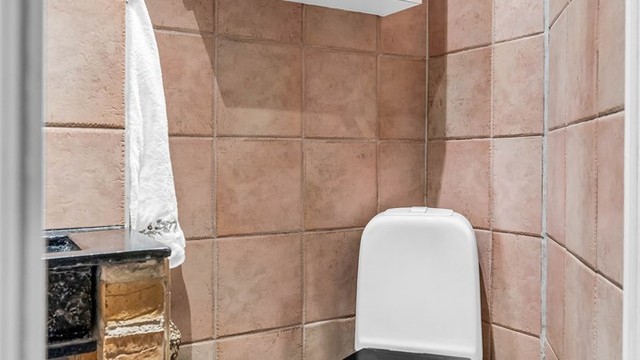 Flislagt baderom med dusj, toalett og servant.