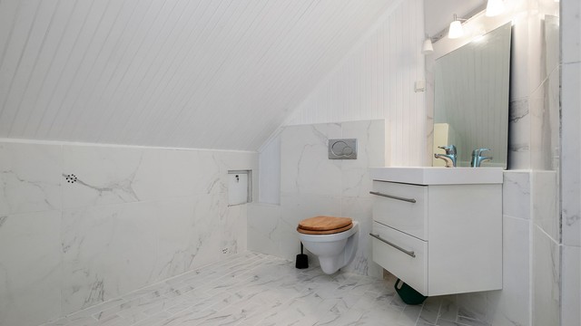 Badet i 2. etasje har flislagt gulv, vegghengt toalett og dusj på gulv.