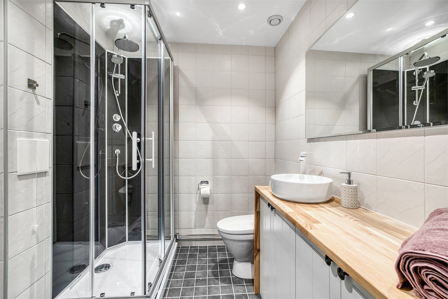 Et pent, flislagt bad med vegghengt toalett og downlights i taket.