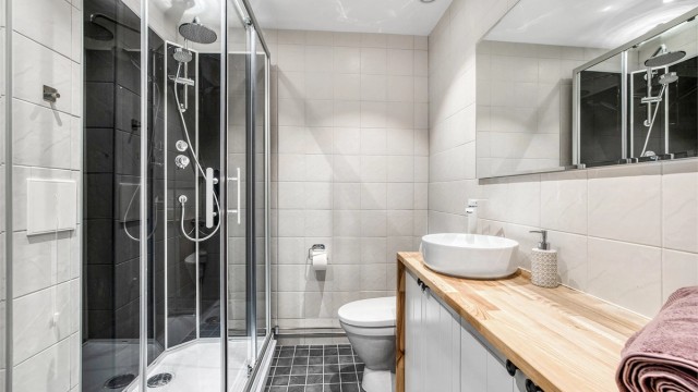 Et pent, flislagt bad med vegghengt toalett og downlights i taket.