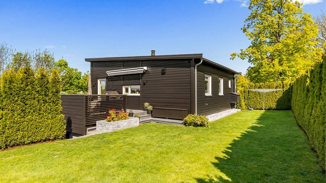 Usjenert hage med plen og hekk som rammer inn eiendommen.