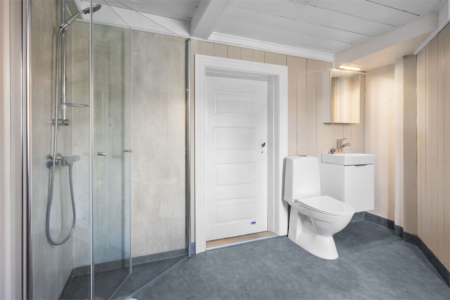 Badet er innredet med toalett og servant med underskap.