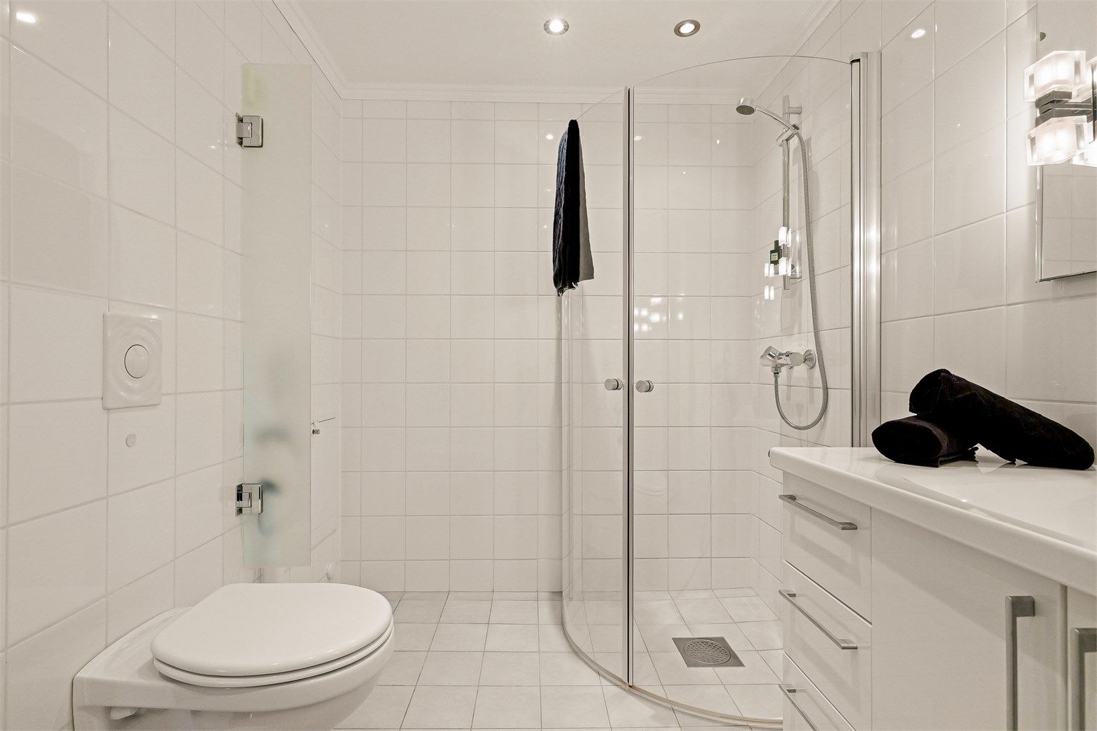Badet er utstyrt med vegghengt toalett og dusjhjørne med innfellbare glassdører - som gjør badet mer romslig.