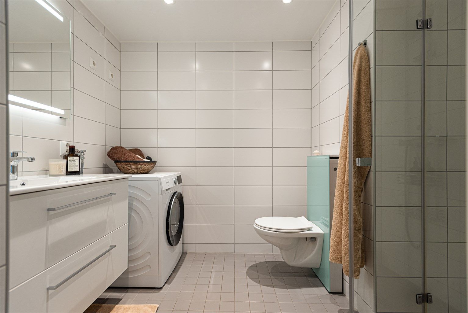 Flislagt bad med vannbåren gulvvarme, downlights i himling og opplegg for vaskemaskin.