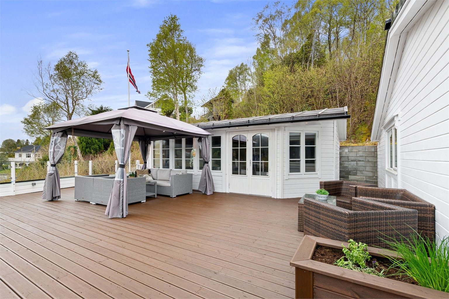 Uteområdet inkluderer en romslig terrasse og en tilhørende utestue.