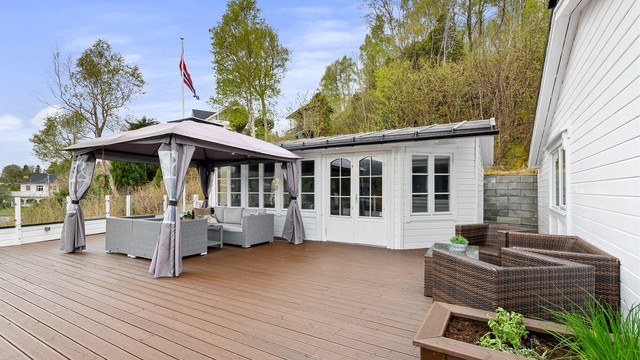 Uteområdet inkluderer en romslig terrasse og en tilhørende utestue.