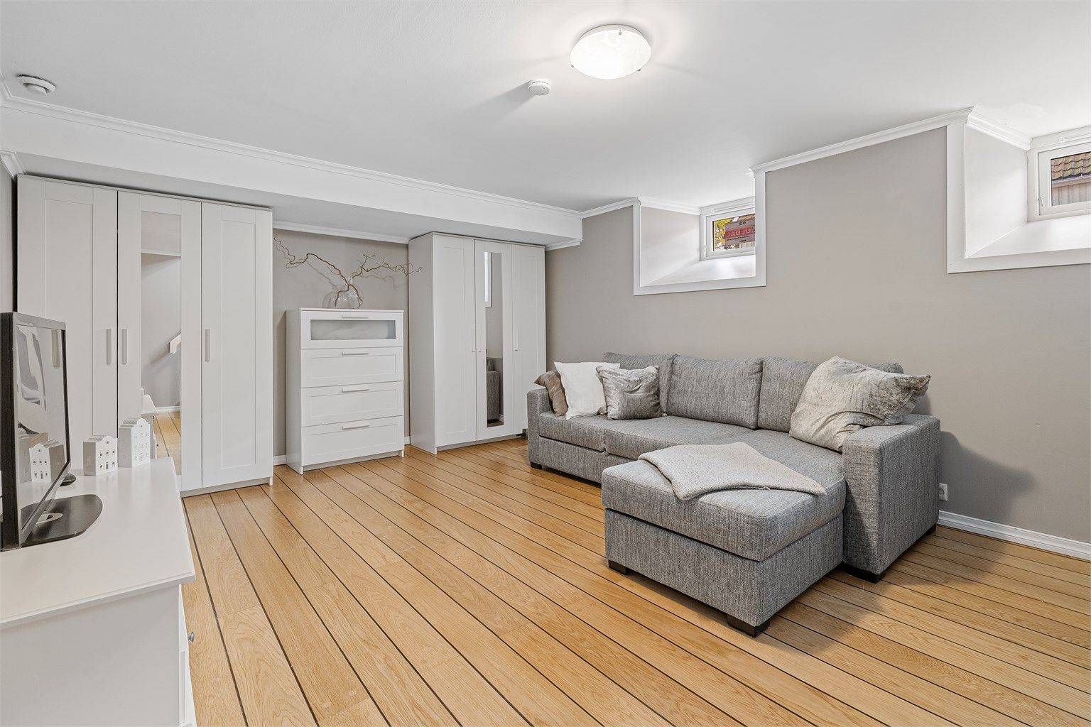 Lys og flott innredet kjellerstue med skipsgulv med varmekabler og store garderobeskap som medfølger