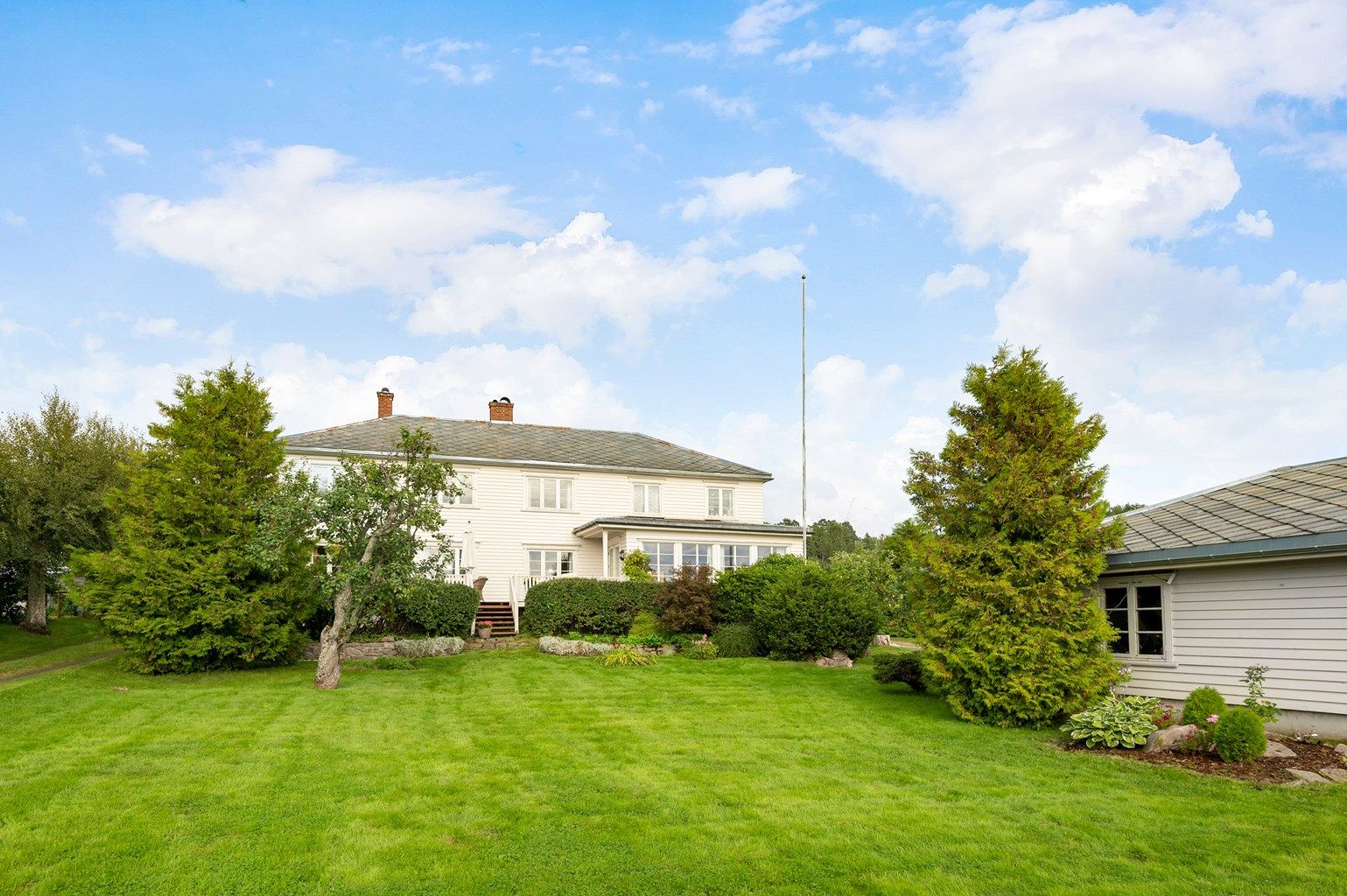 Variert beplantning på eiendommen, store trær og frukttrær.
