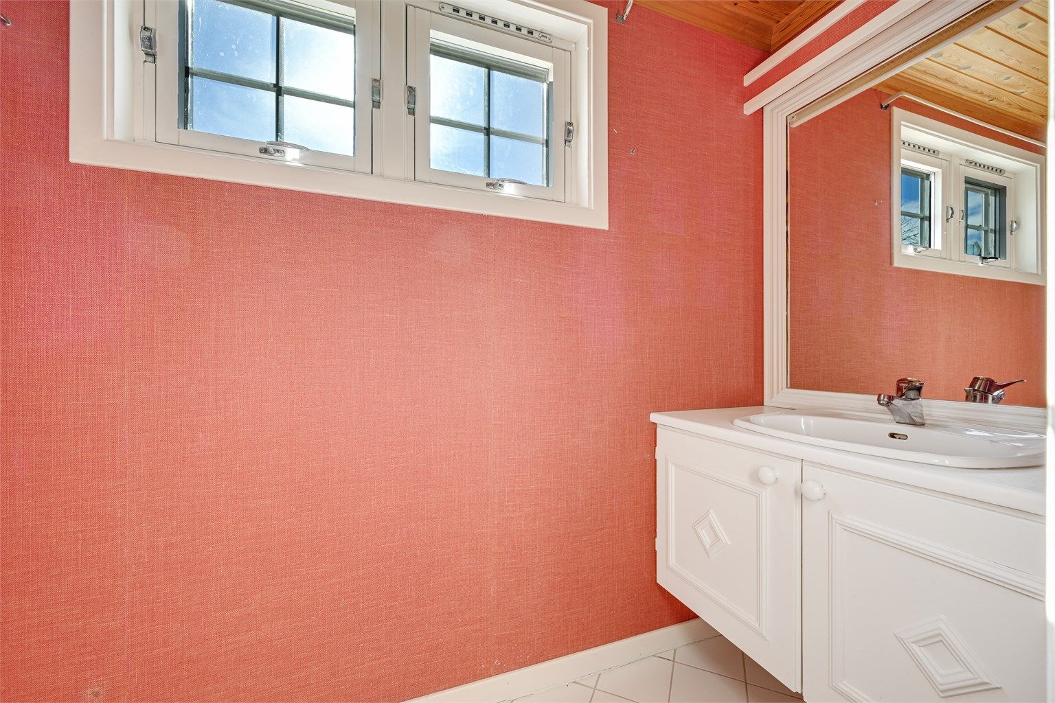 Toalettrommet i første etasje er innredet med toalett, håndvask og speil.