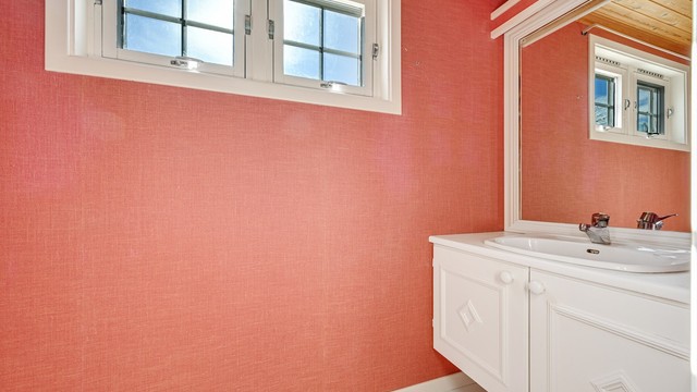 Toalettrommet i første etasje er innredet med toalett, håndvask og speil.