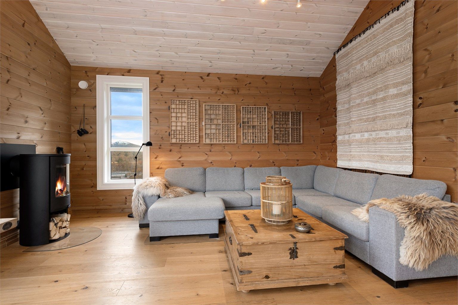 Koselig sofakrok på stuen med peisovn som gir en lun og hyggelig atmosfære