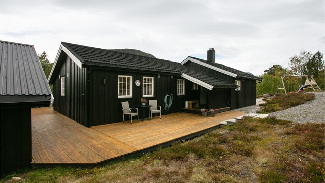 Hytten har stående kledning og tak tekket med takpanner.